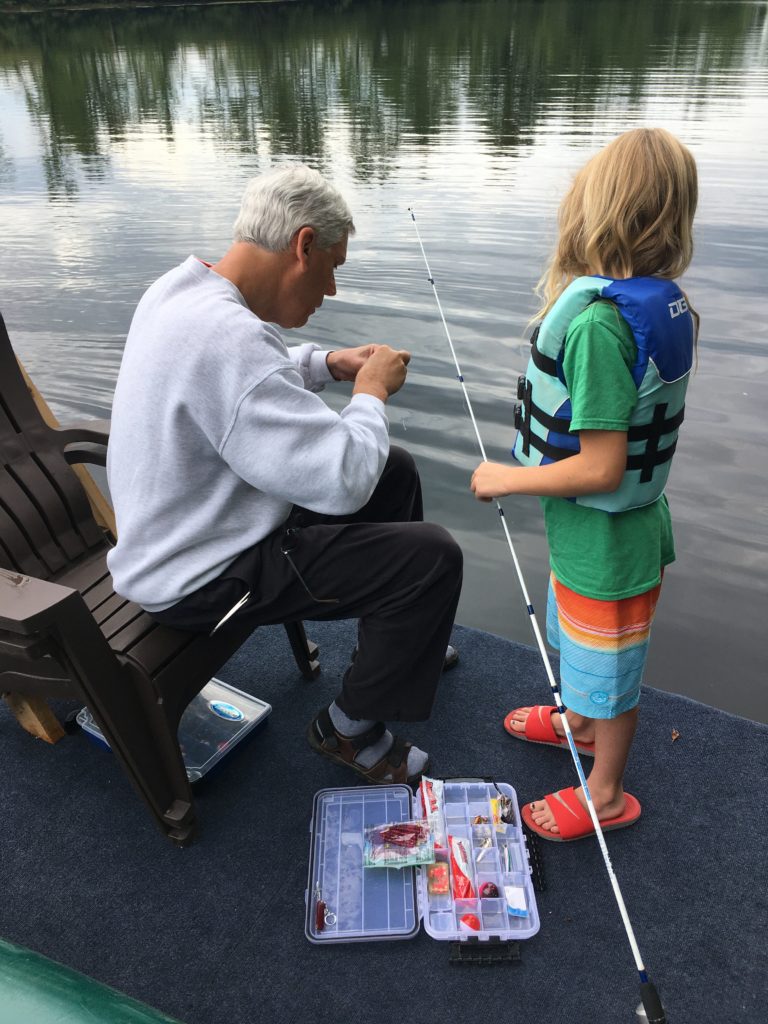 Pop-Pop helping Dillon get bait and a hook on his fishing line.