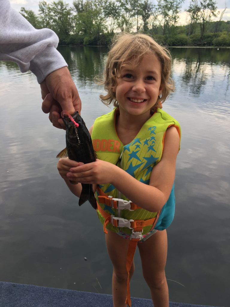 Ainsley holding a fish that she caught with some help from Pop-Pop.