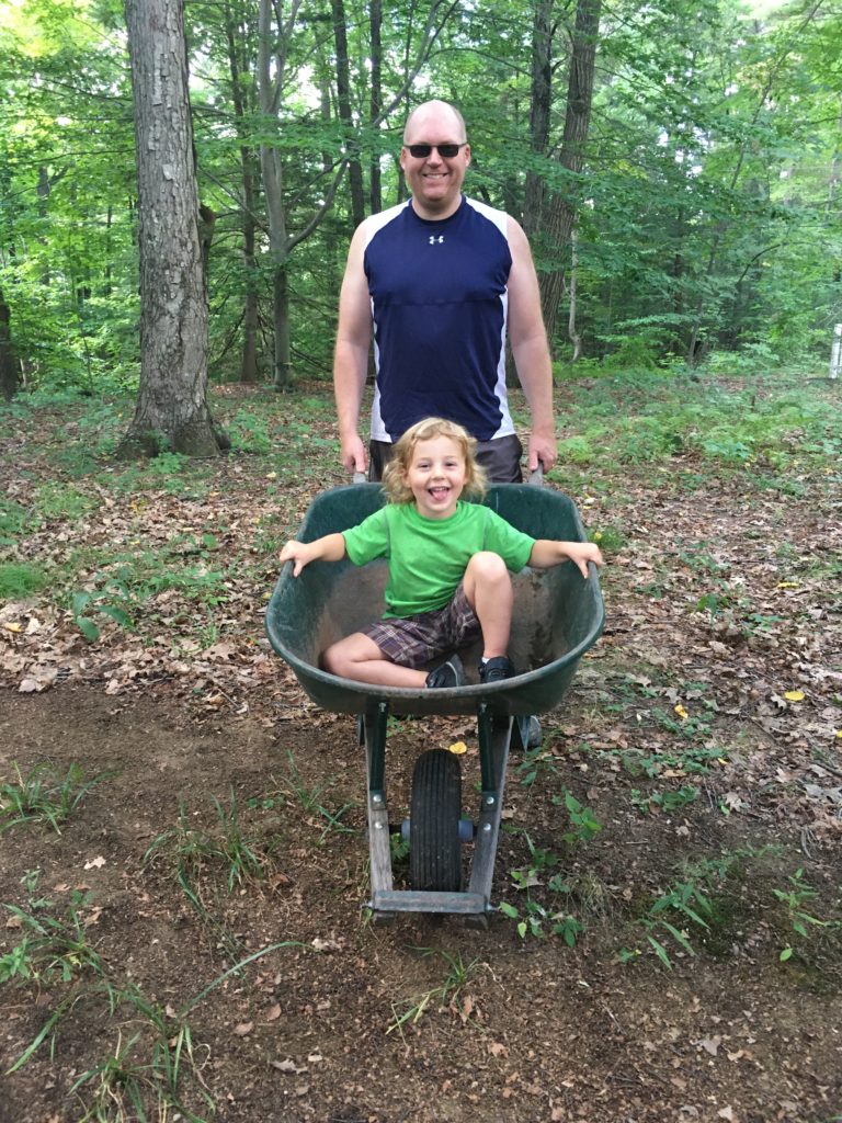 A photo of Kevin giving a wheelbarrow ride to Grayson.