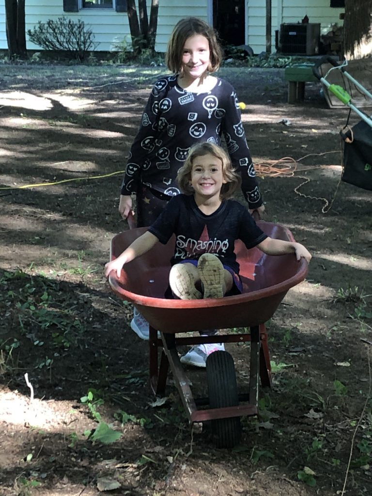 A photo of Rayleigh giving Ainsley a ride in the wheelbarrow