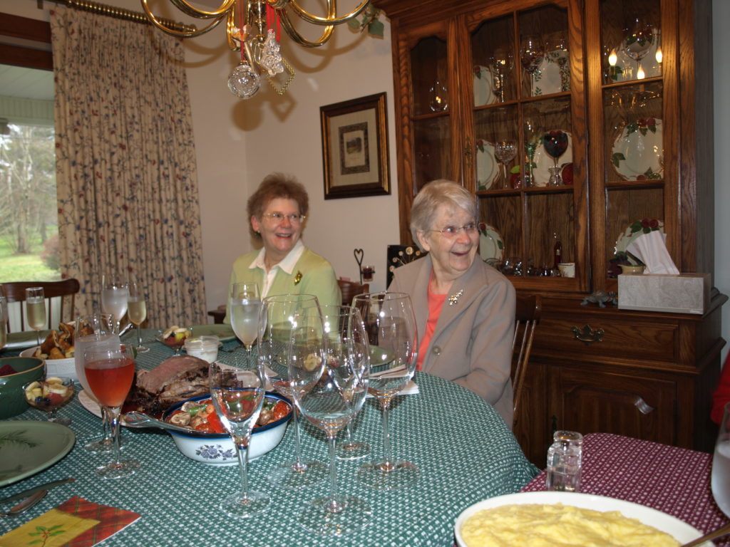 Aunt Ann and Grandma at Jill and Paul's table at Christmas, looking off-camera and laughing at something