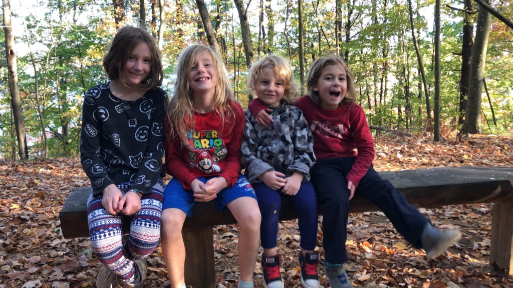 Rayleigh, Dillon, Grayson, and Ainsley resting on a bench at the top of a hill. 