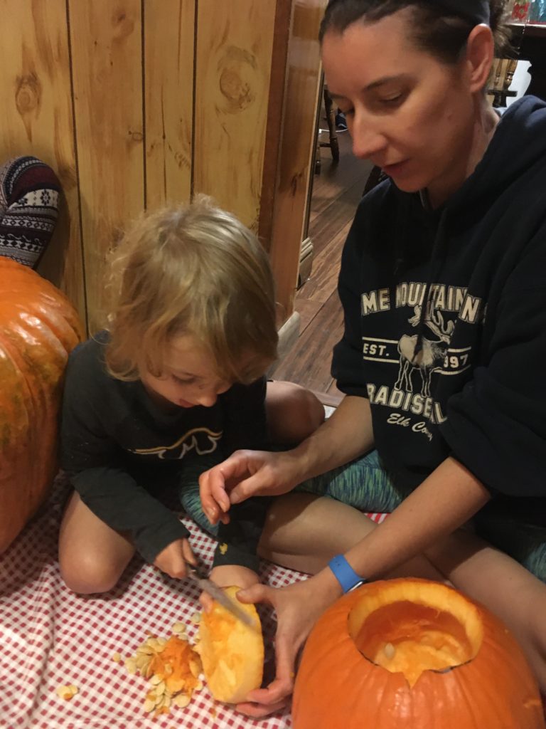 Kelsey helping Grayson trim the excess off of his pumpkin top.