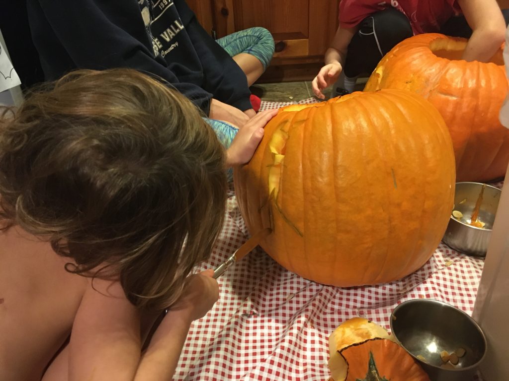 Ainsley carving her pumpkin, which is the silhouette of a cat princess in a dress.