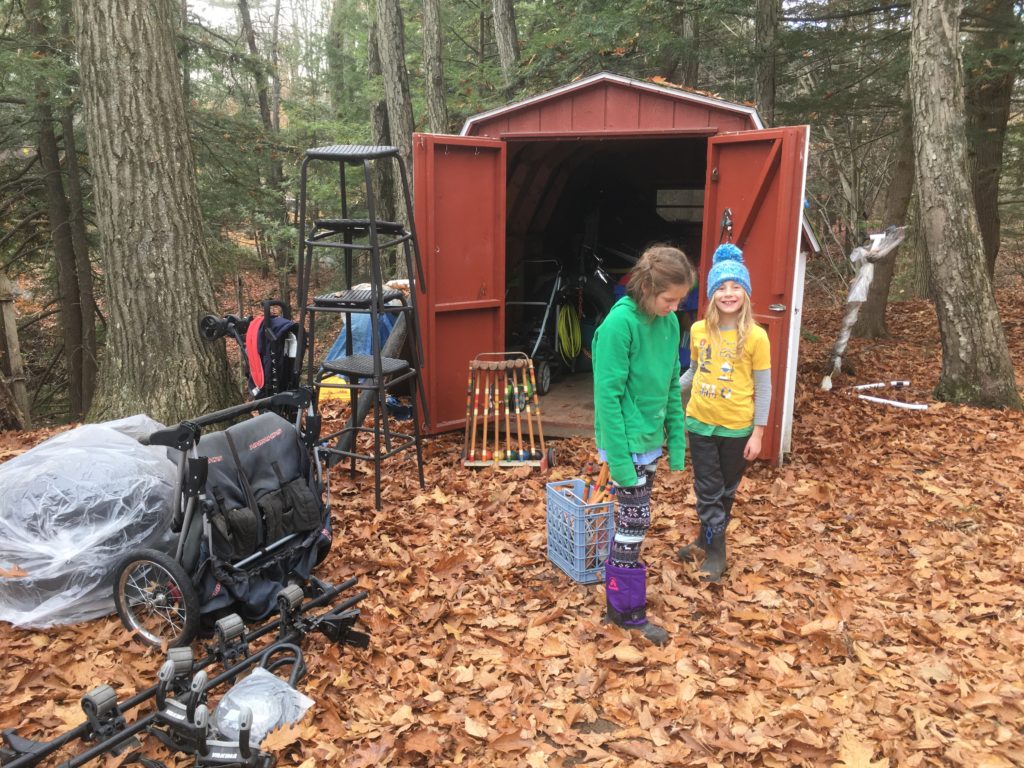 A photo of Rayleigh and Dillon posing outside of the storage shed with several items laying outside, including bar stools and a stroller.