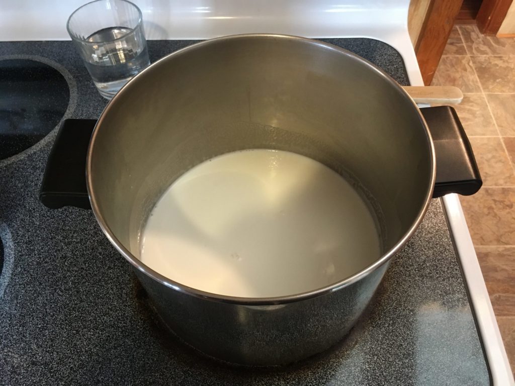 A photo of milk heating on the stove in a stock pot.