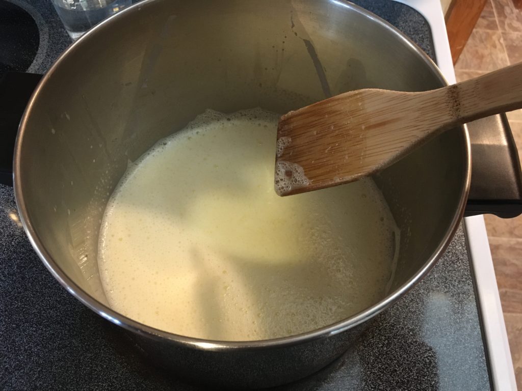 A photo of the milk/egg/sugar mixture on the stove being stirred while it cooks over medium heat.