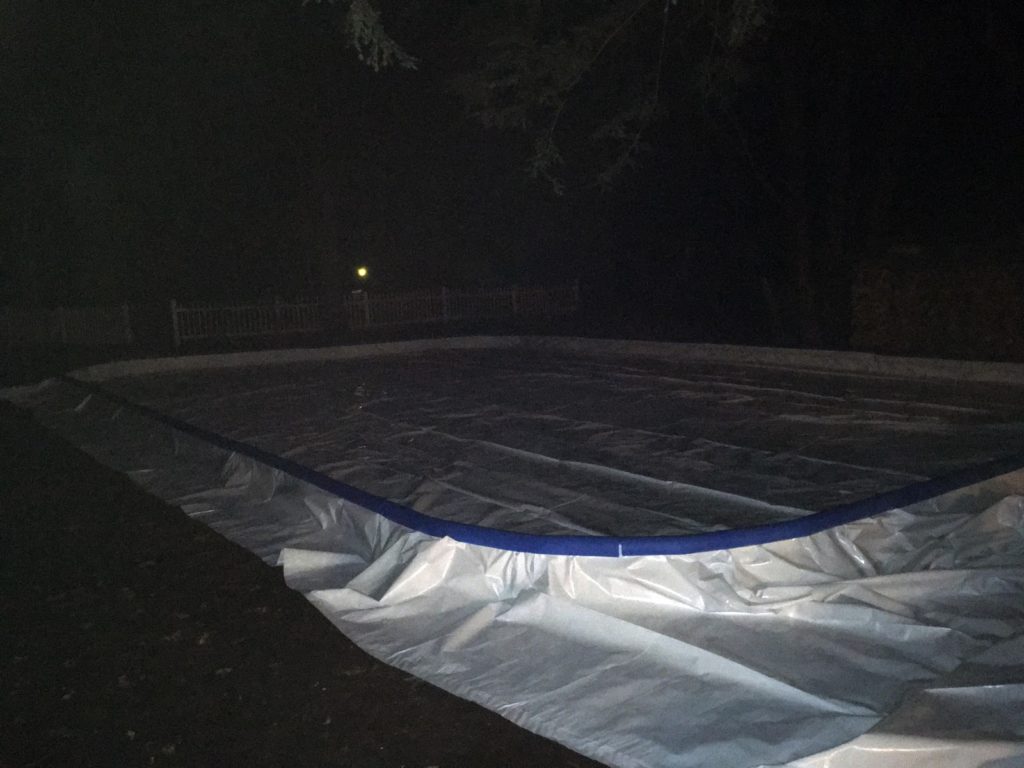 A photo of the finished rink, with liner and foam edge protectors installed, at night.