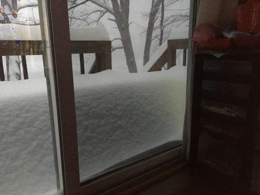 A photo of three feet of snowfall on the deck, viewed through the sliding door.