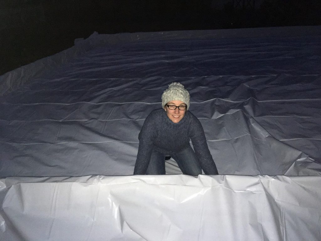 A photo of Kelsey installing the plastic liner inside of the rink frame at night.