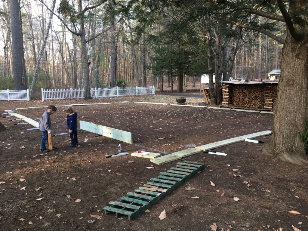 A photo of lumber laid out roughly in a rectangle on the yard.