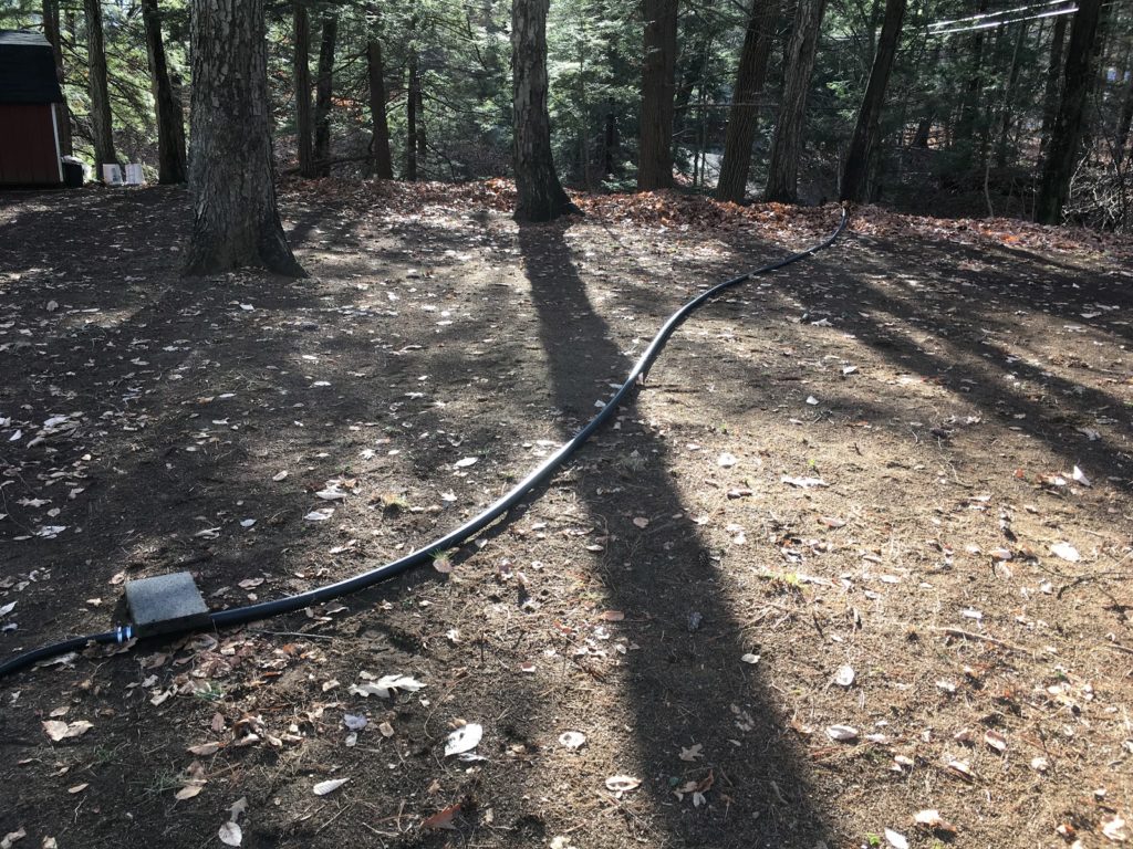 A photo of the water pipe heading across the yard from the hill.