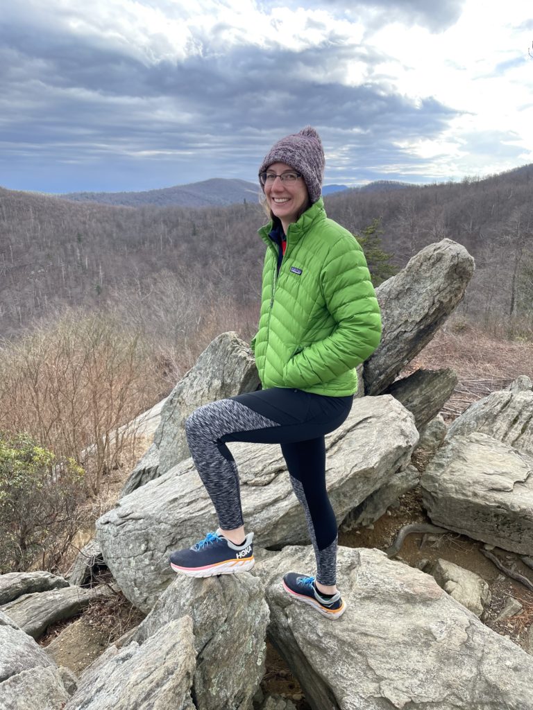 A photo of Kelsey standing on some large rocks with the Appalachian mountains in the background