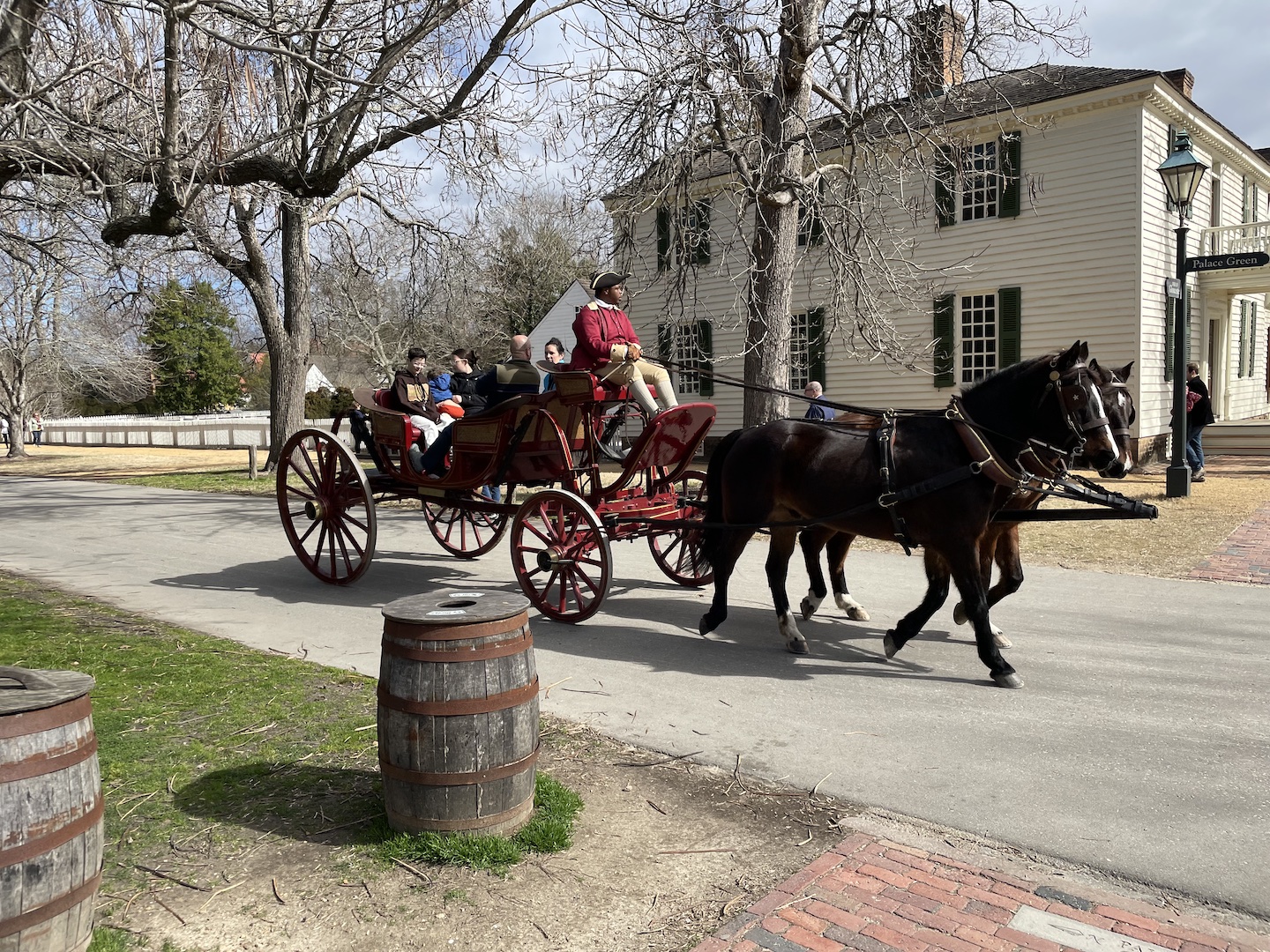 A photo of a horse drawn carriage driven by a Black man in period costume in Colonial Williamsburg