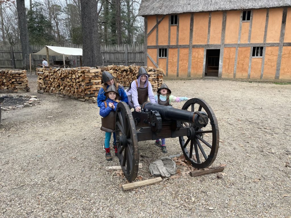 A photo of Grayson, Dillon, Rayleigh, and Ainsley dressed in plate mail and helmets around a 17th century cannon