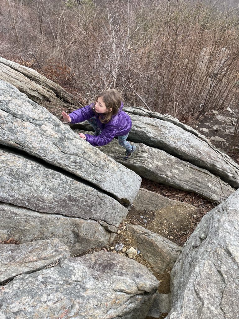 A photo of Ainsley climbing a rock formation in Shenandoah National Park