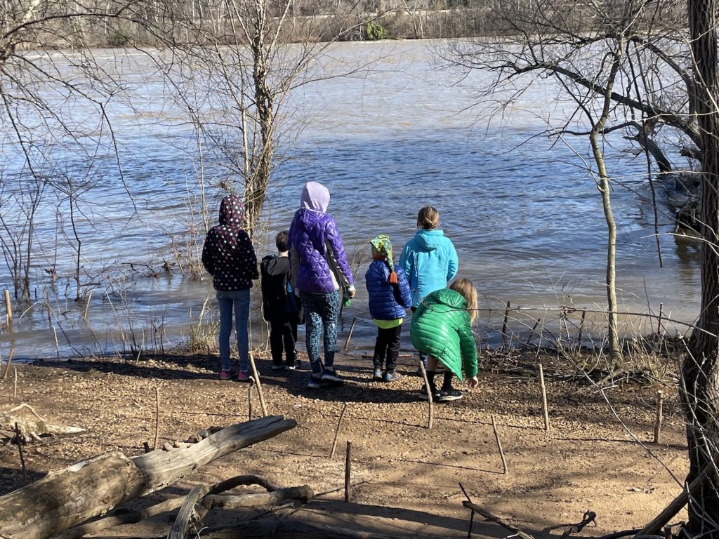 A photo of Mia, Milo, Rayleigh, Grayson, Maisie, and Dillon standing on the bank of the James River