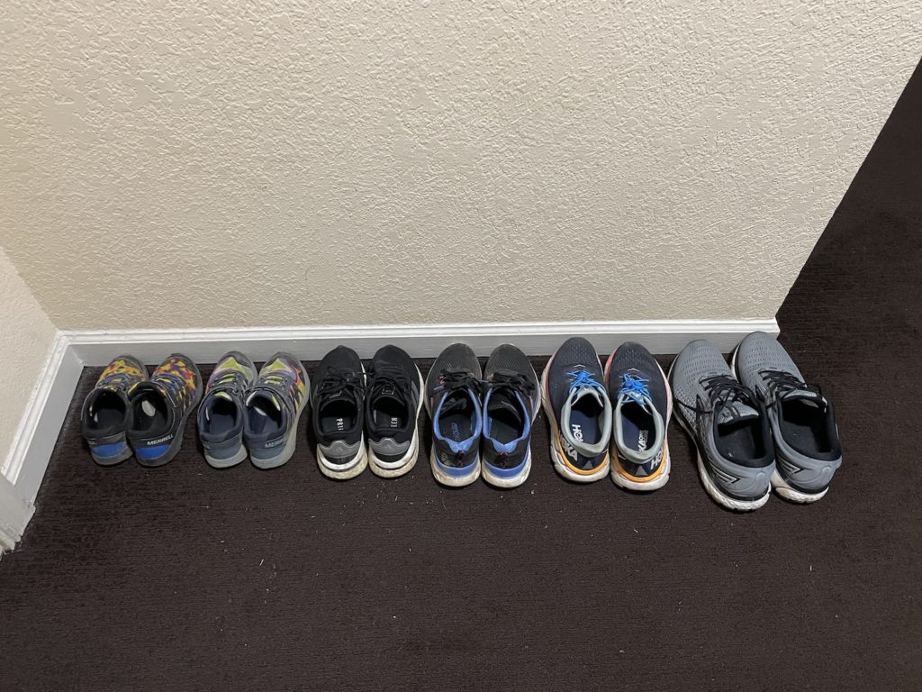 A photo of six pairs of shoes, arranged smallest to largest, on the floor of a hotel room