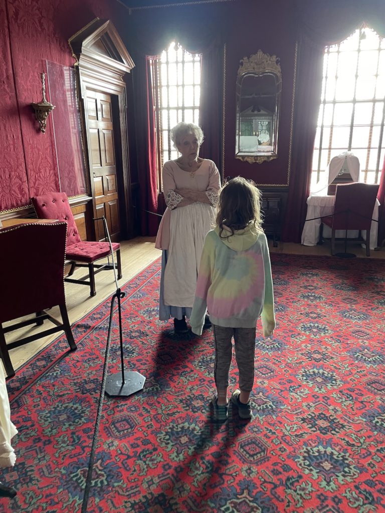 A photo of Ainsley talking to the Governor's Palace tour guide in Colonial Williamsburg