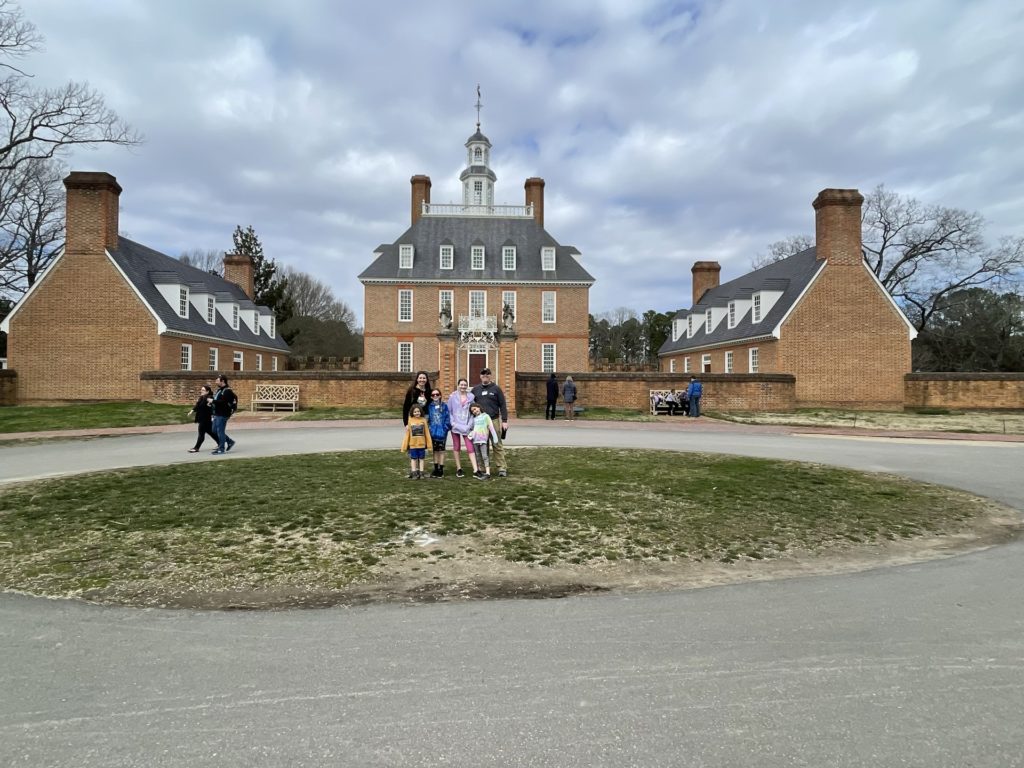 A photo of Kelsey, Grayson, Dillon, Rayleigh, Ainsley, and Kevin outside of the Governor's Palace in Colonial Williamsburg