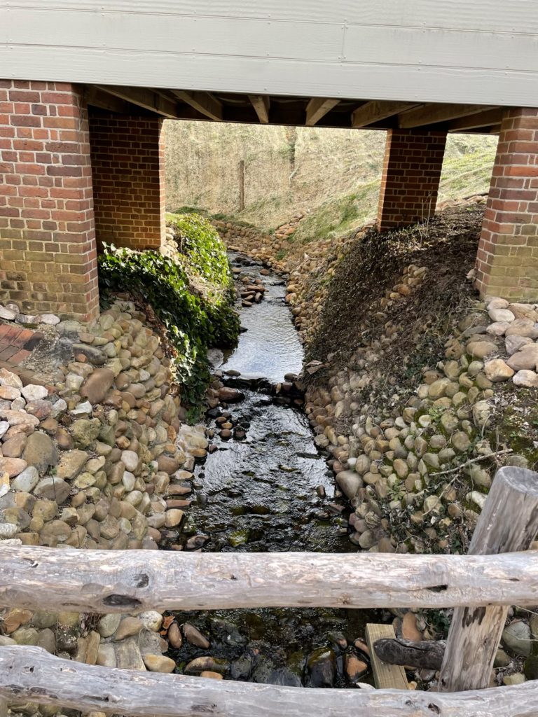 A photo of a stream running under a building in Colonial Williamsburg