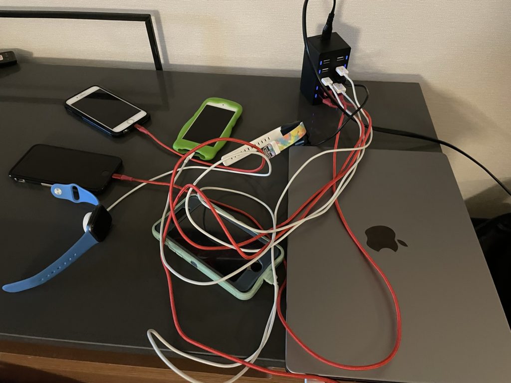 A photo of several phones, watches, and computers charging on a hotel table