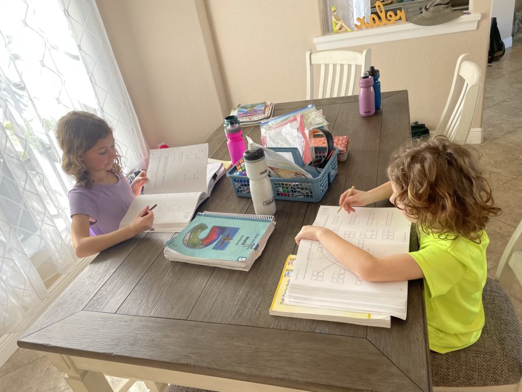 A photo of Ainsley and Grayson doing schoolwork at a table.