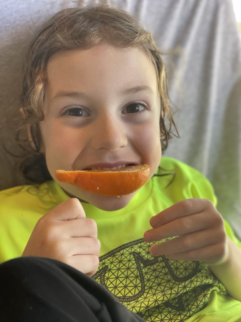 A photo of Grayson eating an orange slice