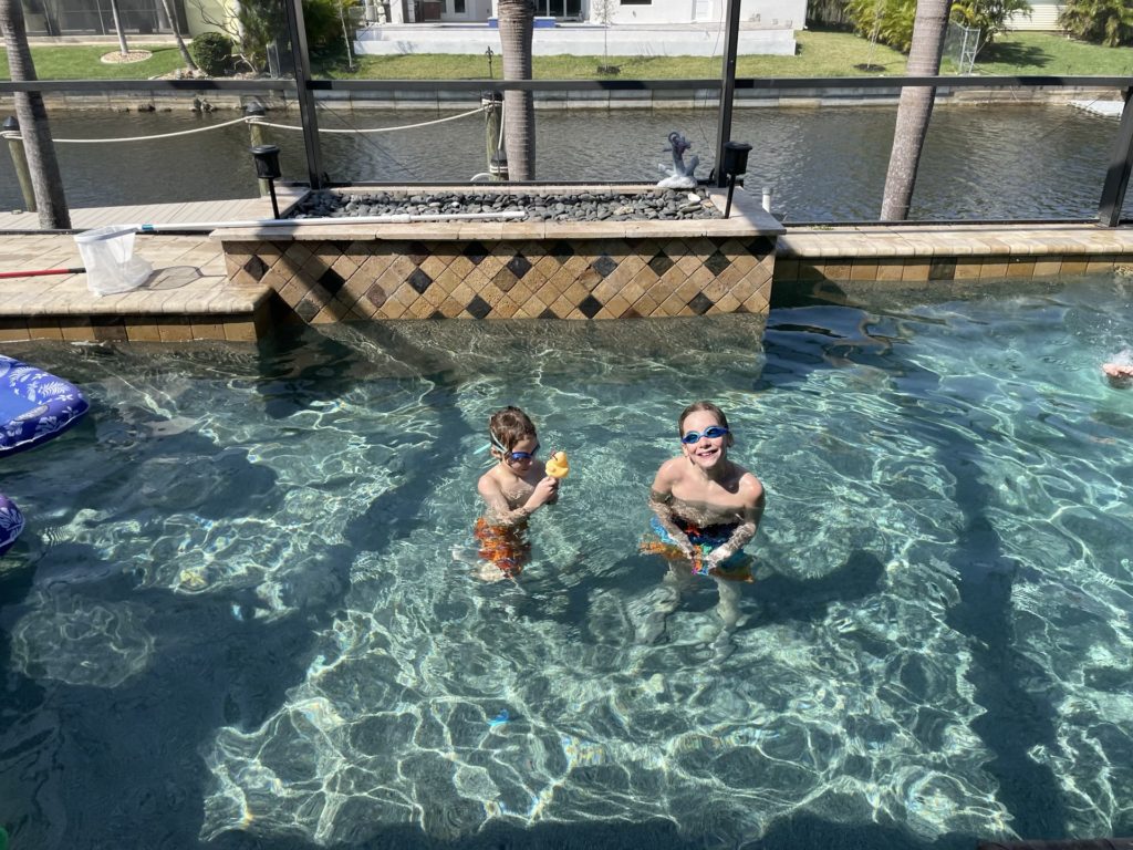 A photo of Grayson and Dillon in the pool with the canal in the background