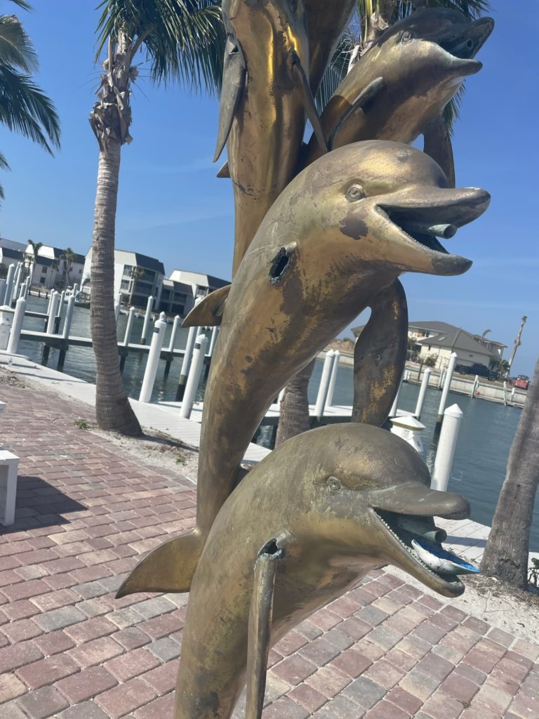 A photo of bronze dolphins with fountain spouts in their mouths that had parts ripped off by hurricane Ian