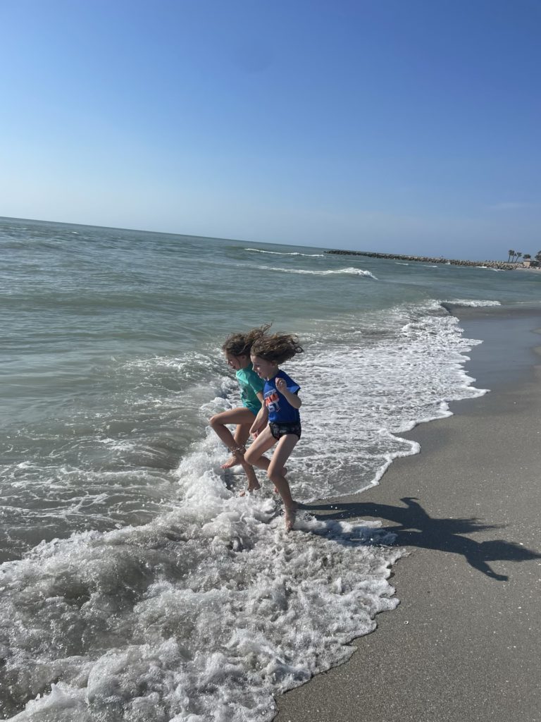 A photo of Ainsley and Grayson jumping in the surf