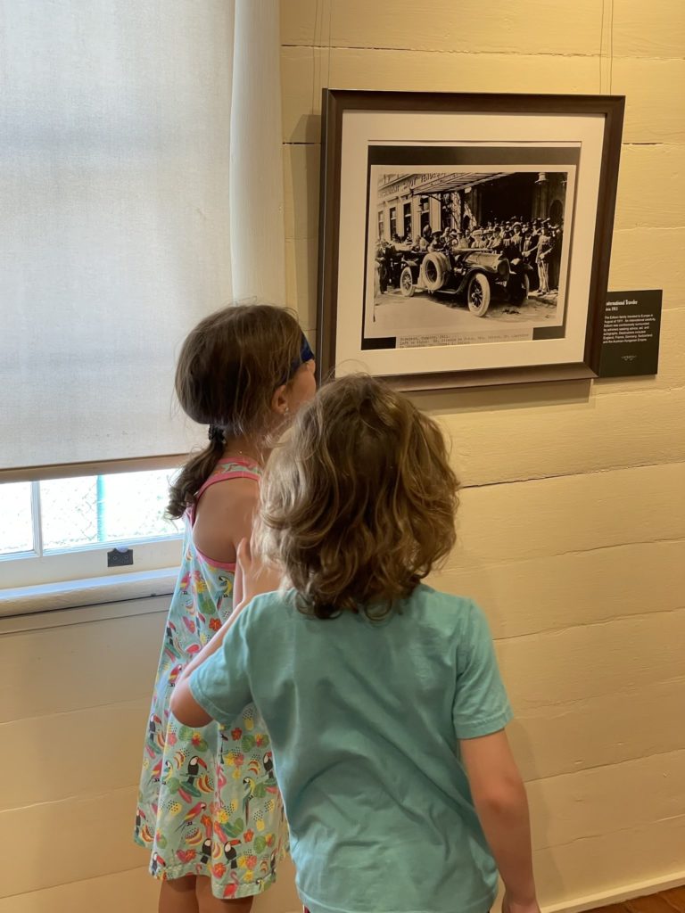 A photo of Ainsley and Grayson admiring a photo of an early 20th century automobile