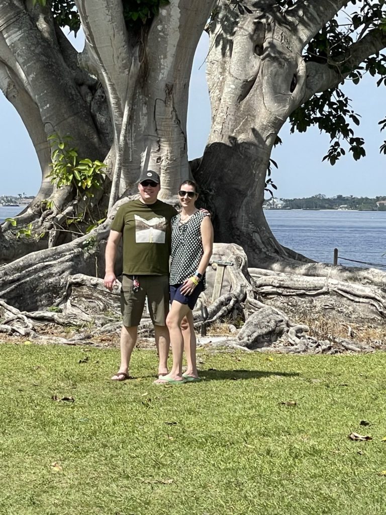 A photo of Kevin and Kelsey in front of a huge banyan tree with sprawling exposed roots