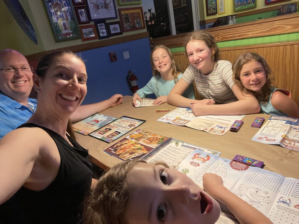 A photo of Kevin, Kelsey, Grayson, Dillon, Rayleigh, and Ainsley at a restaurant table with menus spread out in front of them