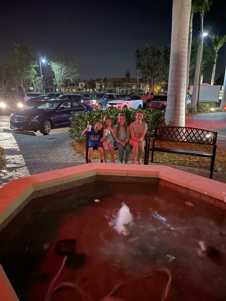 A photo of Grayson, Ainsley, Dillon, and Rayleigh sitting in front of a fountain outside of a restaurant