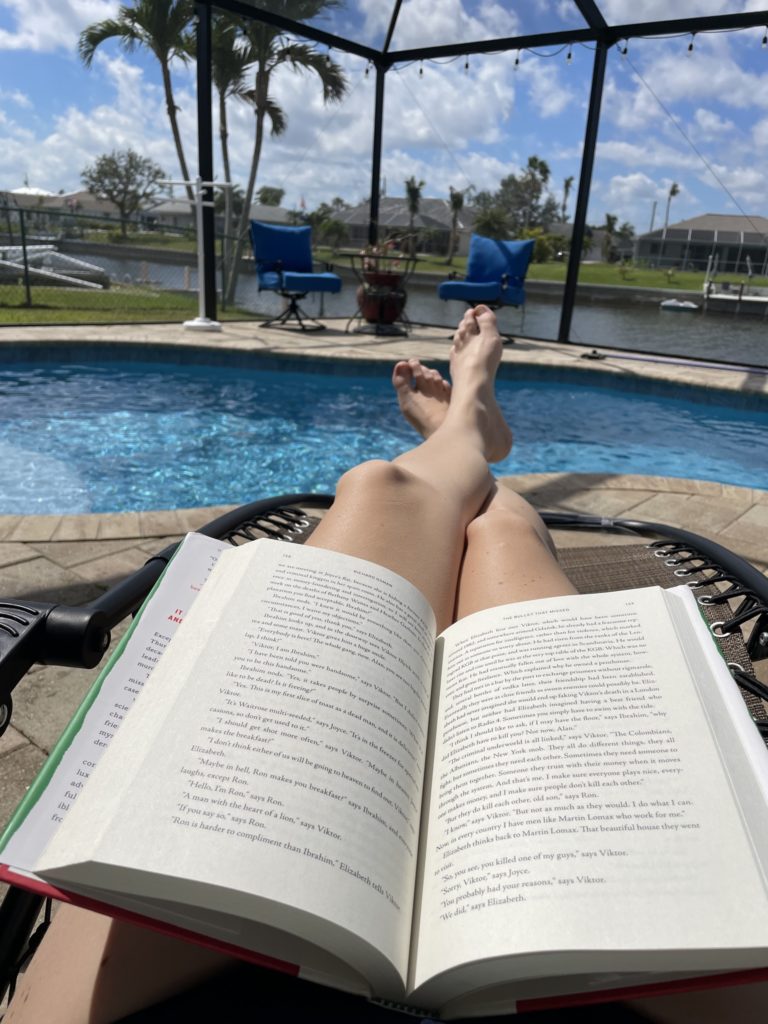 A photo of a book open on Kelsey's lap on the pool deck