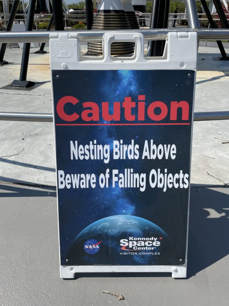 A photo of a sign that reads "Caution: Nesting birds above. Beware of falling objects."
