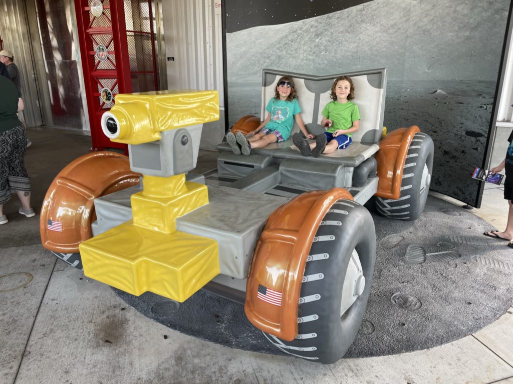 A photo of Ainsley and Grayson on a model moon rover