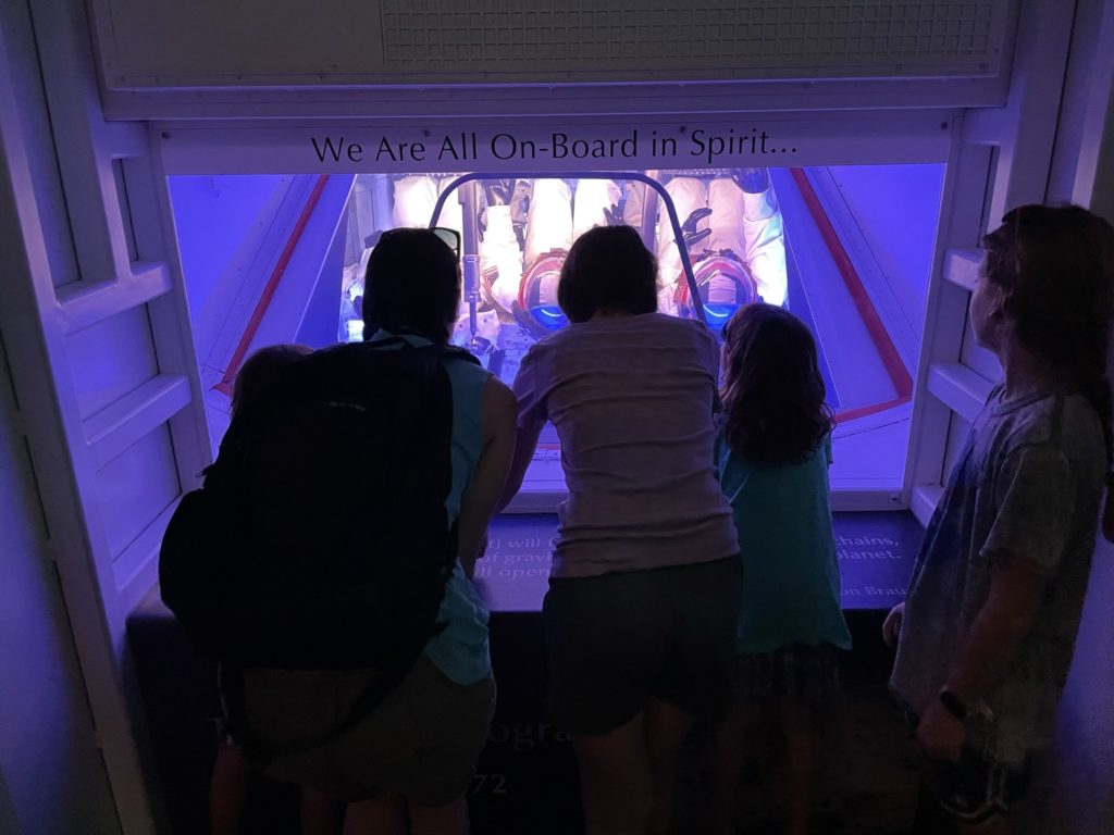 A photo of Grayson, Kelsey, Rayleigh, Ainsley and Dillon looking at a model of the inside of a space capsule
