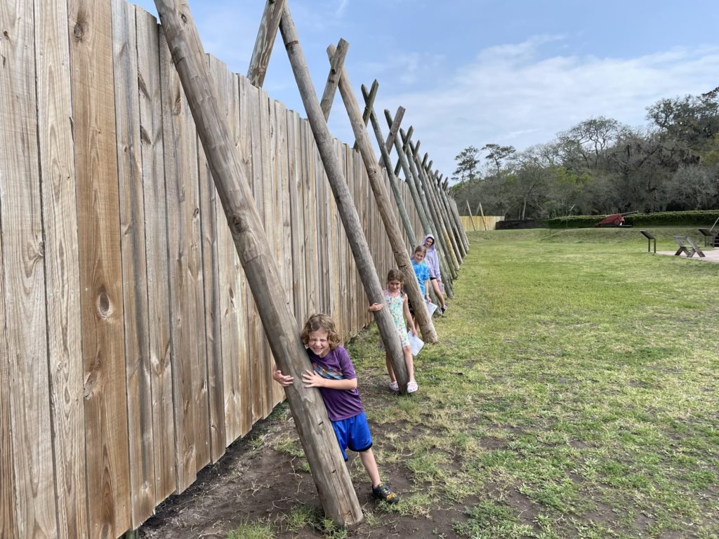 A photo of Grayson, Ainsley, Dillon, and Rayleigh holding support beams for the fort wall