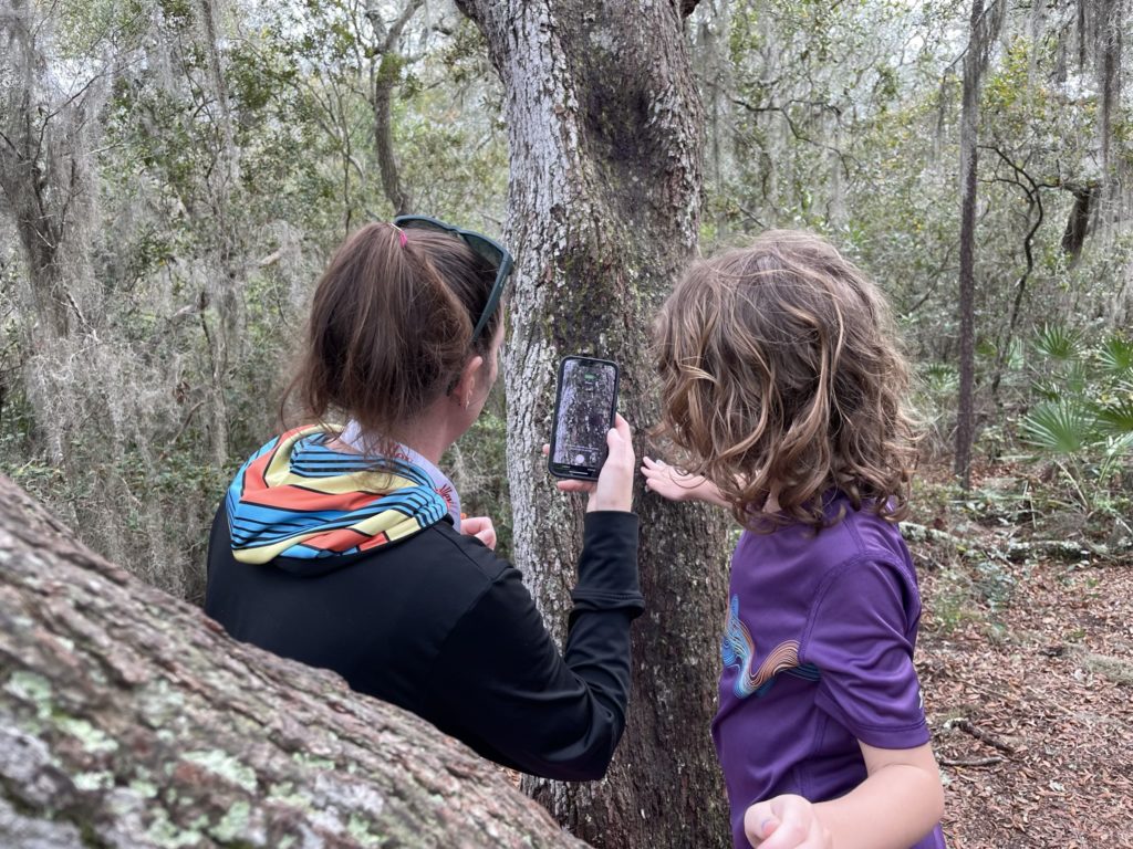 A photo of Kelsey and Grayson using the Seek app on Kelsey's phone to identify an insect