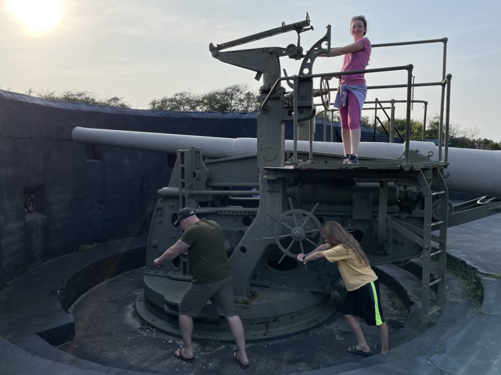 A photo of Kevin, Rayleigh, and Dillon pretending to operate a very large gun mounted on a turret