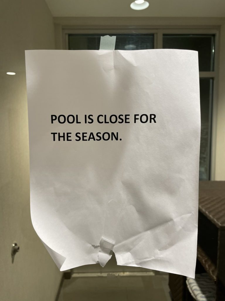 A photo of a sign taped to a glass door that says "Pool is close for the season."