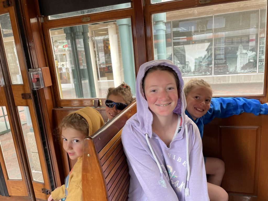 A photo of Grayson, Ainsley, Rayleigh, and Dillon sitting on the trolley