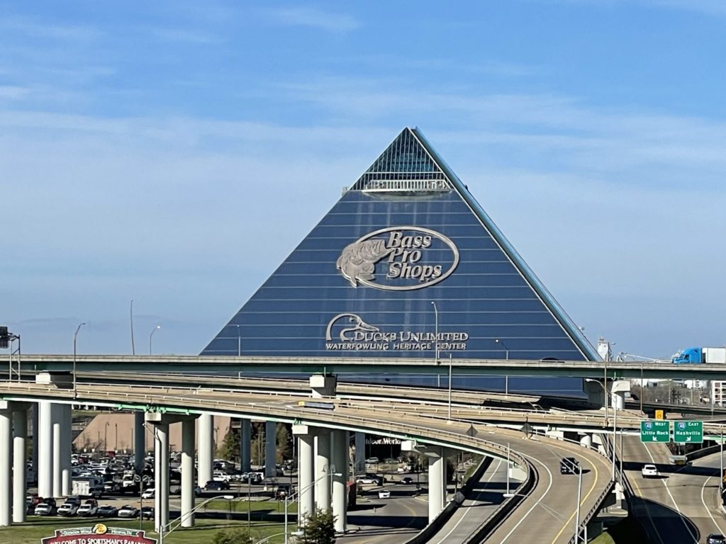 A photo of a gigantic pyramid-shaped building with the Bass Pro Shops logo on it, along with the text Ducks Unlimited Waterfowling Heritage Center