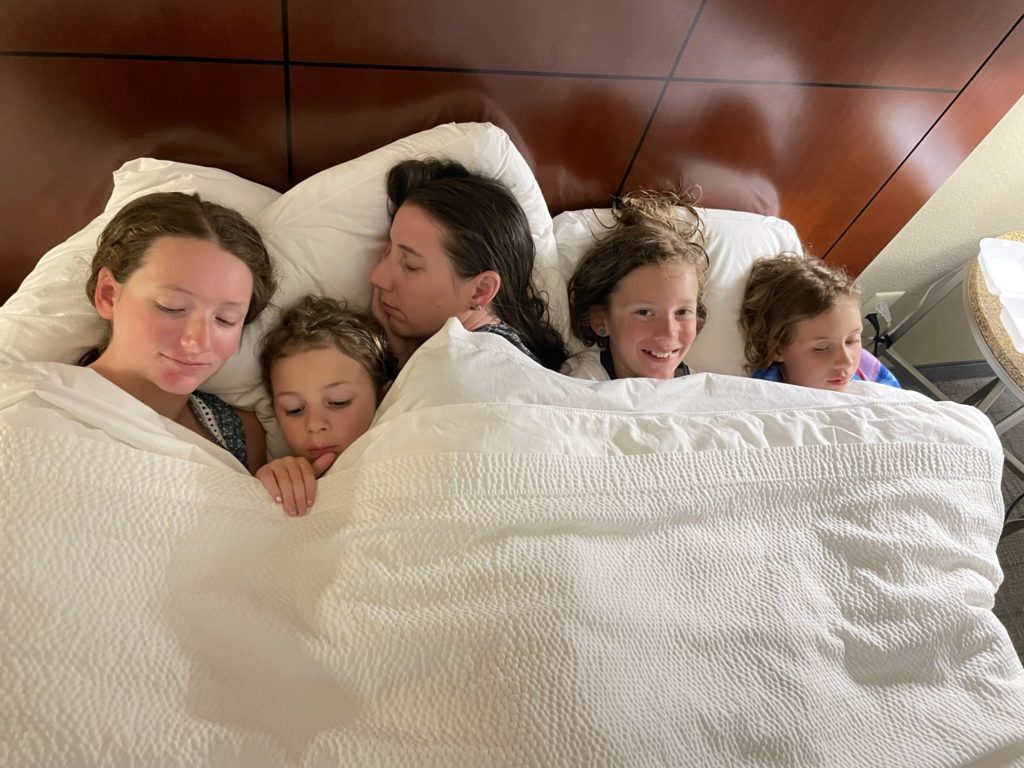 A photo of Rayleigh, Grayson, Kelsey, Dillon, and Ainsley all smushed together in a queen bed