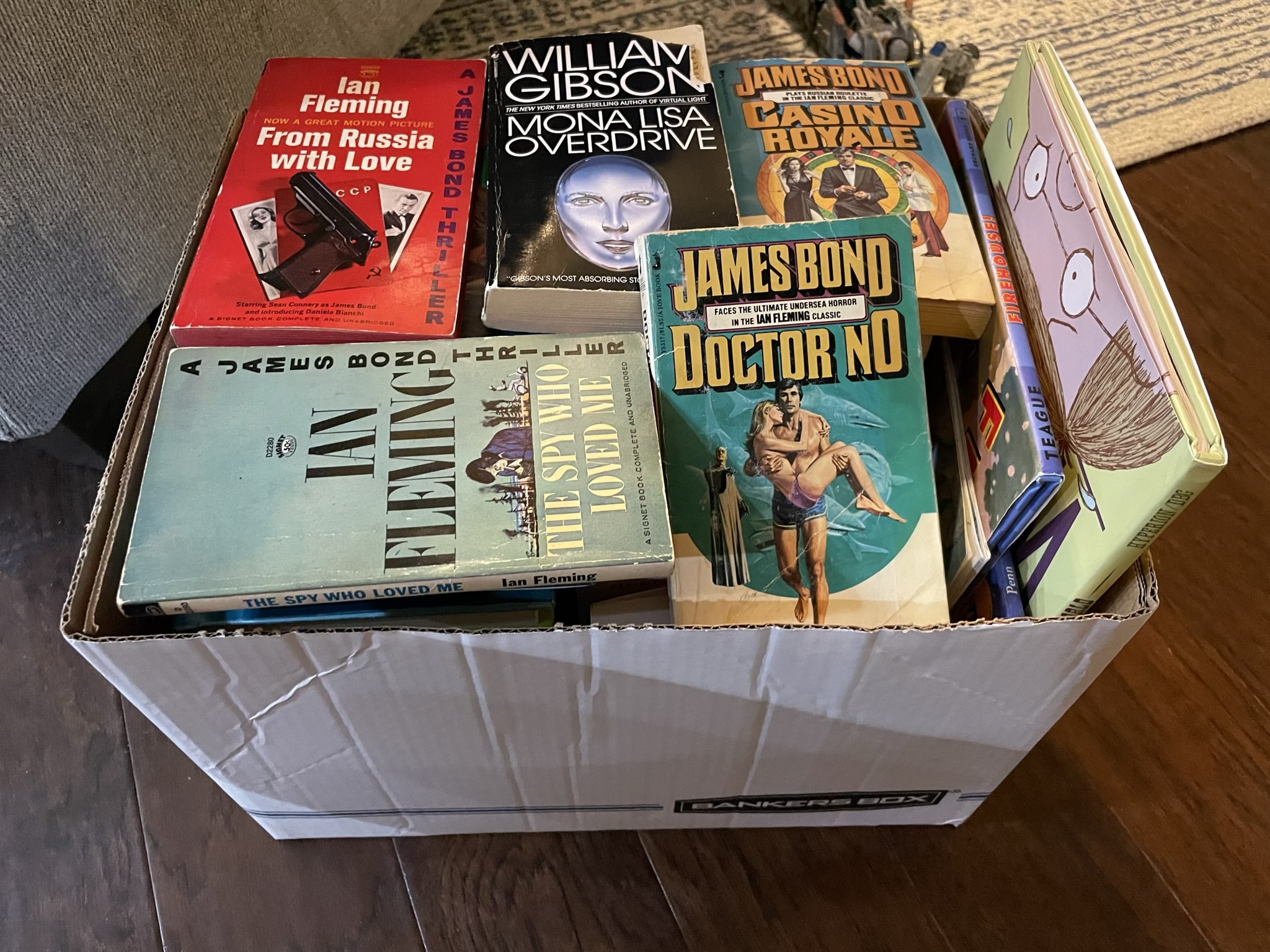A photo of a large box of books, with the covers of From Russia with Love, The Spy Who Loved Me, Doctor No, and Casino Royale, all by Ian Fleming, and Mona Lisa Overdrive by William Gibson.