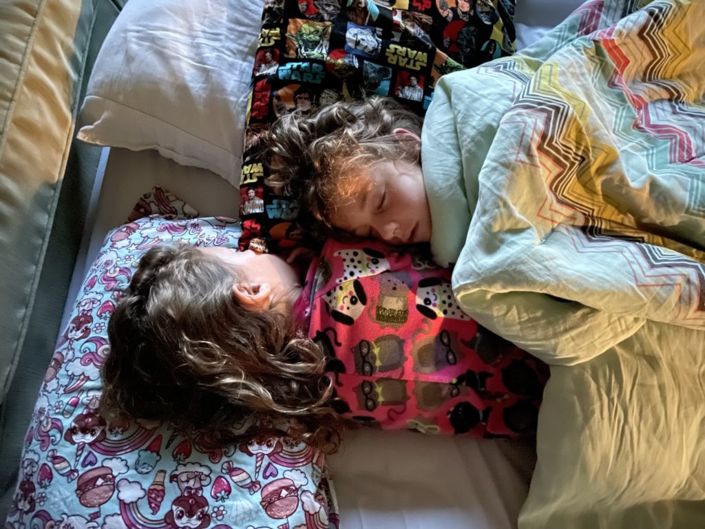 A photo of Ainsley and Grayson snuggled up next to each other asleep in bed in the morning