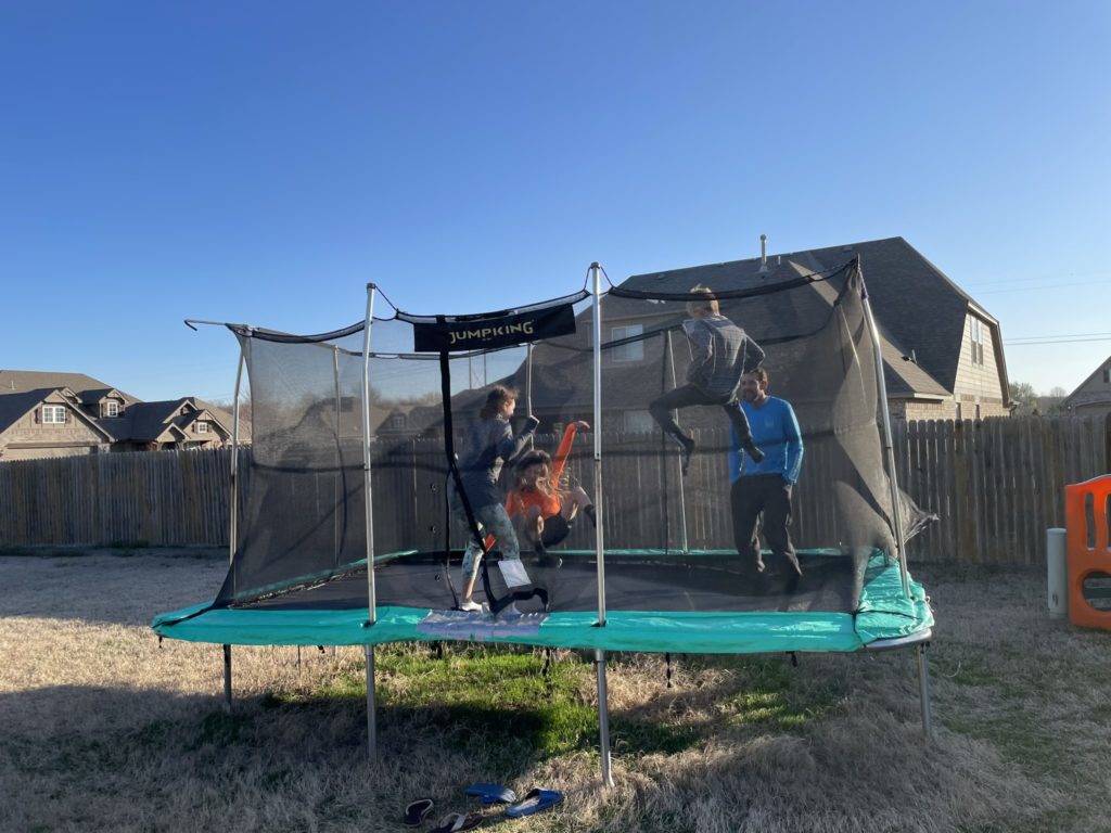 A photo of Rayleigh, Dillon, Peter Elias, and Peter jumping on the trampoline
