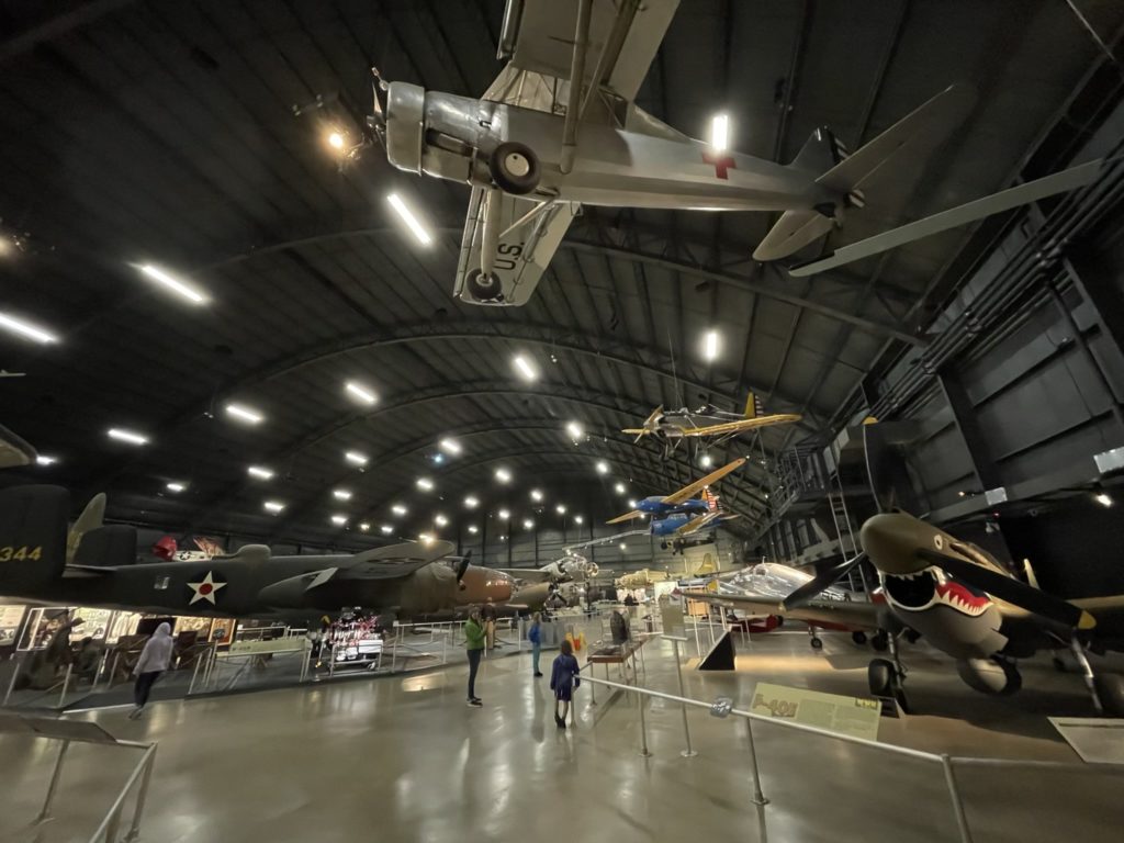 A wide-angle shot of the hanger containing the World War 2 era planes, showing several planes on the ground as well as suspended from the ceiling